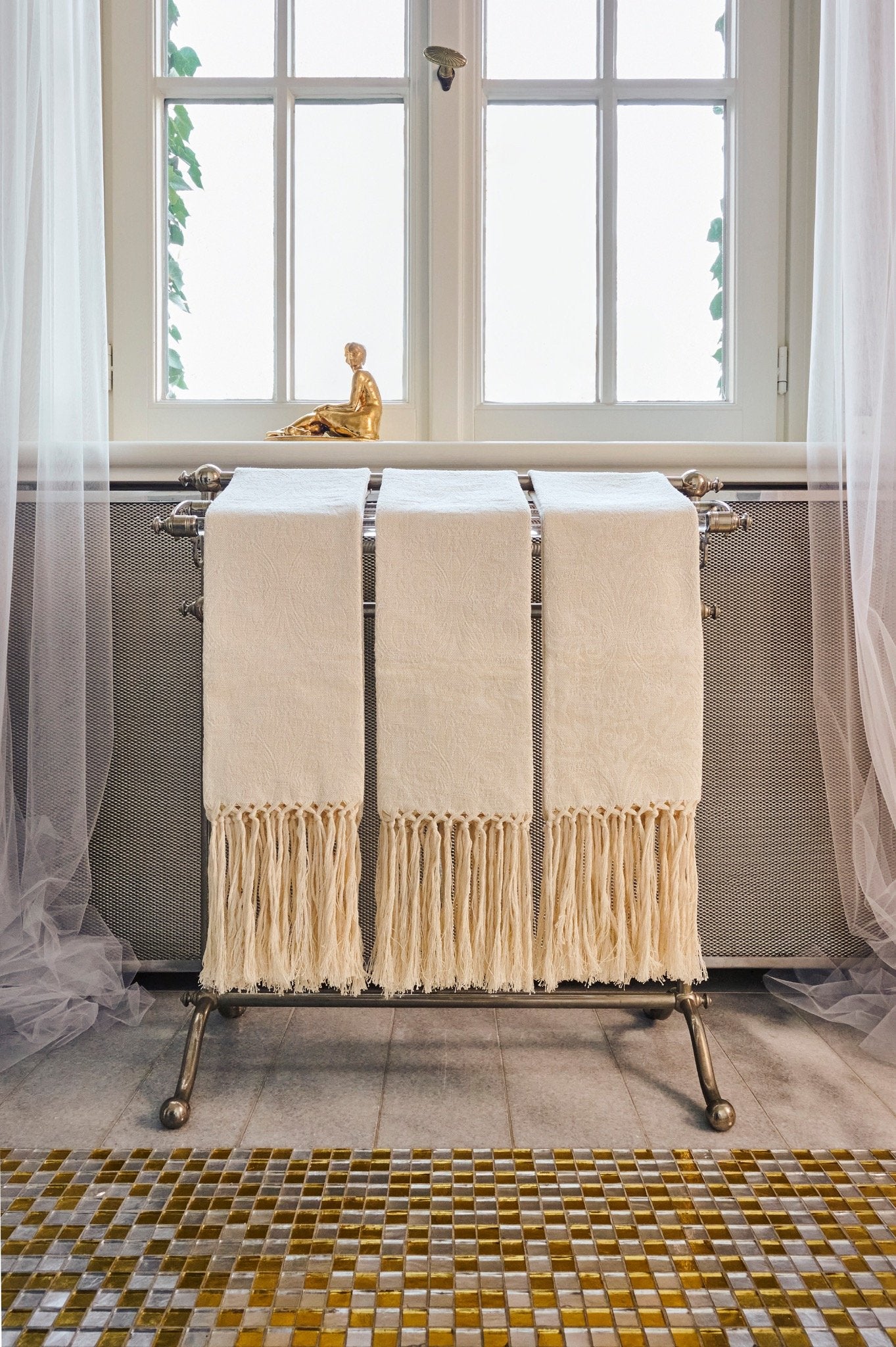 White linen hand towels with hand-knotted fringe hanging on a vintage towel holder. 